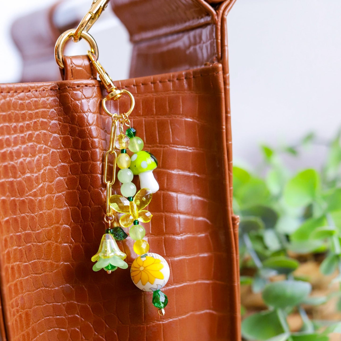 Decorative keychain with yellow and green assorted beads attached to a brown textured bag.