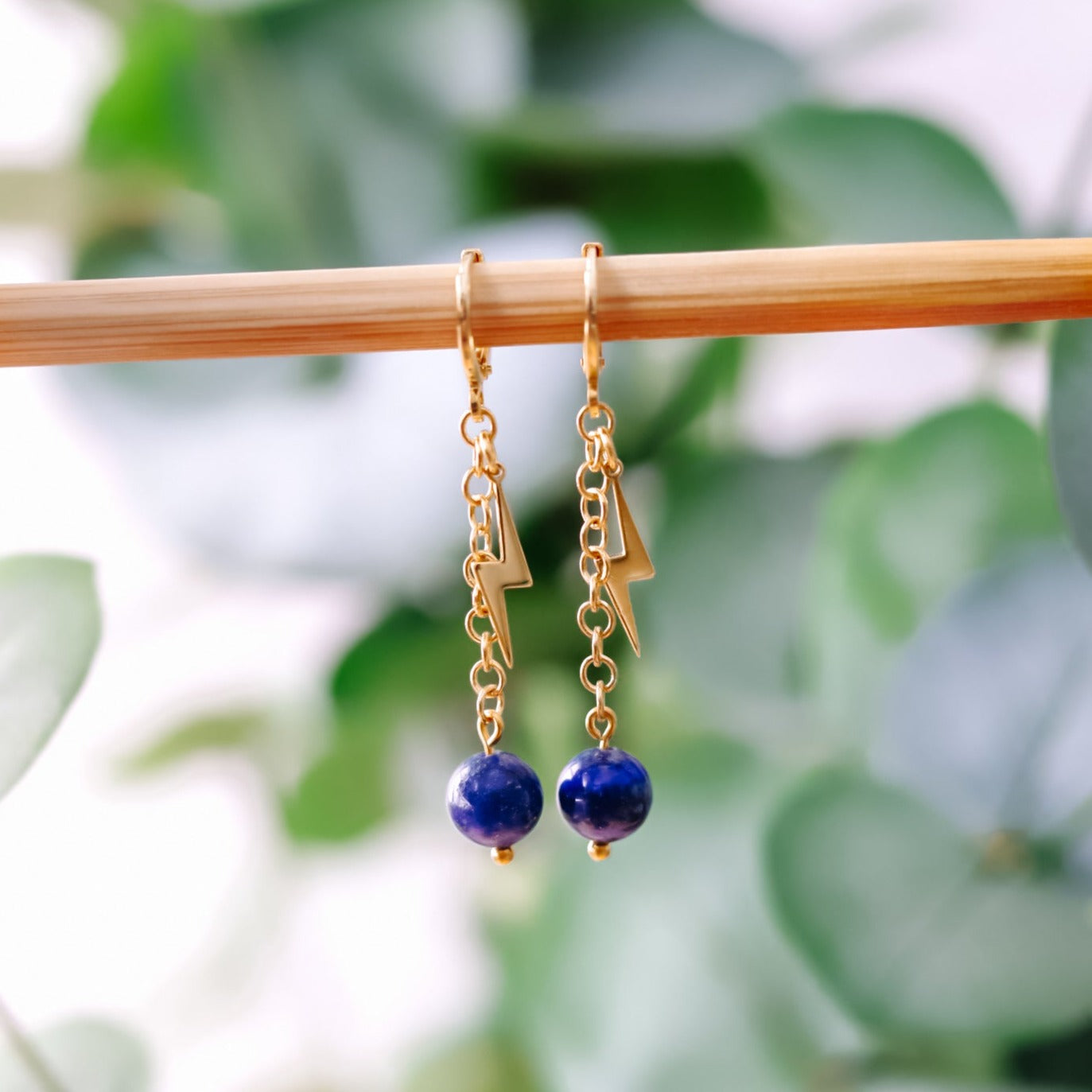 Earrings with blue beads on gold chain and lightning bolt charm